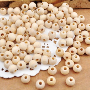 May include: A large pile of natural wood beads, with a white lace doily underneath. The beads are round and have a smooth, unfinished surface.
