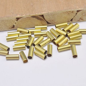 May include: A pile of gold-colored metal end caps for cords or wires. The end caps are cylindrical and have a smooth finish.