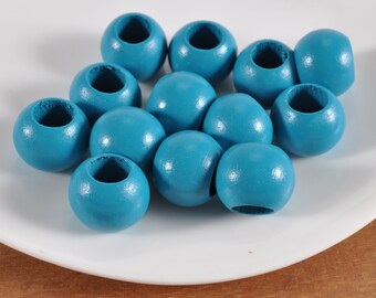 May include: A collection of teal blue wooden beads with a hole in the center of each bead. The beads are arranged in a circular pattern on a white surface.