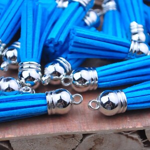 May include: A collection of bright blue tassels with silver metal caps. The tassels are made from a soft, fluffy material and are ideal for adding a touch of colour and texture to any project.