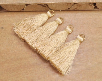 May include: Four gold tassel trim with gold metal rings. The tassels are made of a soft, silky material.