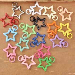 May include: A selection of star-shaped swivel clasps in a range of colours: red, silver, white, black, orange, yellow, green, blue, pink, and purple. These clasps are suitable for keychains, jewellery, or other craft projects.