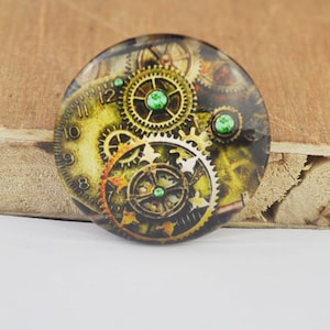 May include: A round, gold-toned, steampunk-style clock face with green gears and accents. The clock face has Roman numerals and a detailed design of gears and cogs.