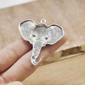 May include: Silver-toned metal elephant charm pendant with a textured surface. The charm has a loop at the top for attaching to a necklace or bracelet.