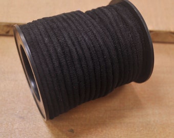 May include: A spool of black suede cord, wound tightly around a black plastic bobbin.