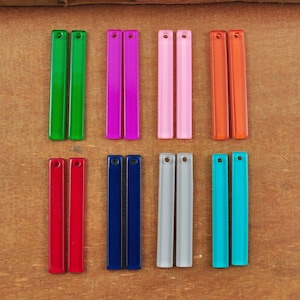 May include: Twelve pairs of acrylic rectangular beads in various colours, including green, purple, pink, orange, red, blue, grey, and turquoise. The beads are arranged in two rows of six pairs.