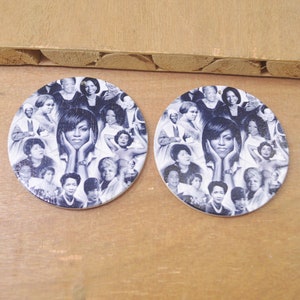 May include: A pair of round wooden earrings with a collage of black and white images of famous women. The earrings feature a central image of a woman with her chin resting on her hands.