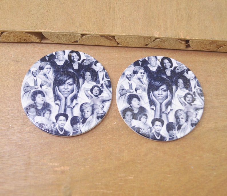 May include: A pair of round wooden earrings with a collage of black and white images of famous women. The earrings feature a central image of a woman with her chin resting on her hands.