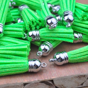 May include: A group of bright green tassel keychains with silver metal caps. The tassels are made of a soft, fuzzy material.