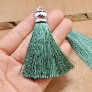 May include: A green silk tassel with a silver metal top. The tassel is about 3 inches long and is perfect for adding a touch of elegance to any project.