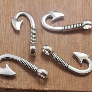 Op de afbeelding: Vier zilverkleurige metalen haken met een vishaakontwerp. De haken zijn allemaal in verschillende maten en vormen.