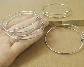 May include: Three silver bangle bracelets with a simple design. The bracelets are made of thin metal and have a spring closure.