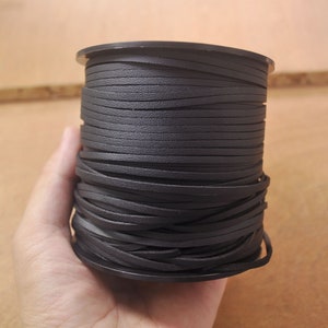 May include: A spool of black leather cord, wound tightly and ready for crafting projects.