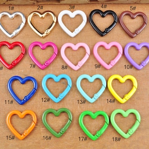 Peut inclure: Dix-huit fermoirs en métal en forme de cœur de différentes couleurs, notamment argent, or, rouge, rose, bleu, vert, orange et jaune. Chaque fermoir est numéroté de 1 à 18.