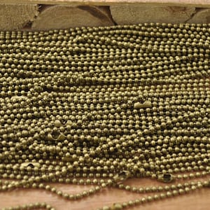 Può includere: Primo piano di un mucchio di catena a sfera in ottone. La catena è composta da piccole perle rotonde collegate tra loro. La catena è una scelta popolare per la creazione di gioielli, portachiavi e altri lavoretti.