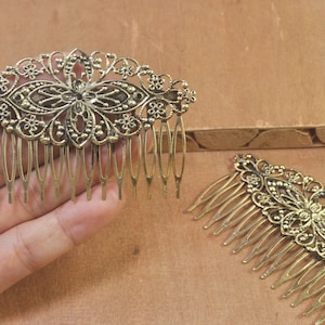 May include: Two gold metal hair combs with intricate floral designs. The combs have a decorative, filigree pattern and are ideal for adding a touch of elegance to any hairstyle.