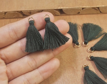 May include: A set of ten dark green fabric tassels with gold metal rings. The tassels are approximately 1 inch long.