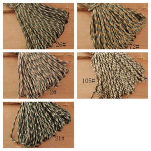 May include: A collection of five bundles of camouflage paracord rope in various color combinations. Each bundle is labeled with a number. The colors include shades of green, brown, tan, and black, creating a textured appearance.