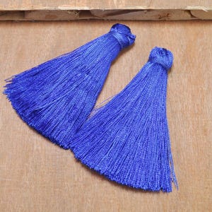 May include: Two blue silk tassels with a long fringe. The tassels are tied together at the top.