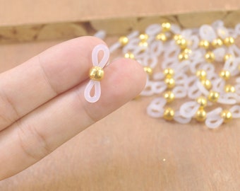 Può includere: Catena per occhiali in plastica bianca con perline dorate. La catena ha un anello ad ogni estremità per essere fissata agli occhiali.