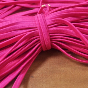 May include: A close-up of a bundle of bright pink elastic cord. The cord is soft and flexible, and it is perfect for crafting projects.
