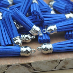 May include: A pile of blue suede tassels with silver metal tops. The tassels are approximately 5 cm long.