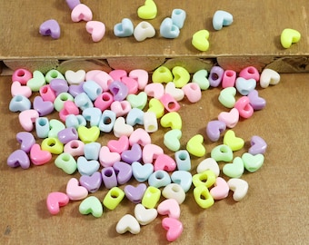 May include: A large assortment of colorful plastic heart-shaped beads in various pastel shades, including pink, purple, blue, green, and yellow.