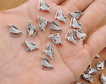 Puede incluir: Una colección de abalorios de metal plateados en forma de patines de hielo. Los abalorios están esparcidos sobre una mano, algunos se superponen.