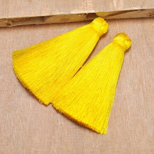 May include: Two bright yellow tassel trims, each with a long, flowing fringe. The tassels are made of soft, silky material and are perfect for adding a touch of color and texture to any project.