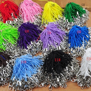 May include: Assortment of 12 colors of string with silver clasps. The strings are bundled together and labeled with numbers 1 through 12.