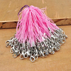 Puede incluir: Un paquete a granel de charms de teléfono de cuerda rosa con cierres de metal plateado.