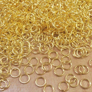 Puede incluir: Un mont&oacute;n grande de anillos de salto dorados, un tipo de anillo de metal utilizado en la fabricaci&oacute;n de joyas.