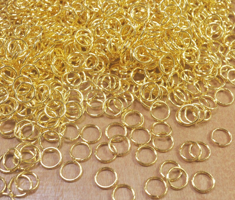 Puede incluir: Un mont&oacute;n grande de anillos de salto dorados, un tipo de anillo de metal utilizado en la fabricaci&oacute;n de joyas.
