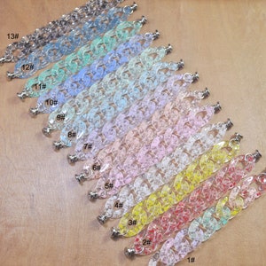 May include: A set of 13 clear plastic chain links with different colors and glitter embedded in the plastic. The chain links are numbered 1 through 13.
