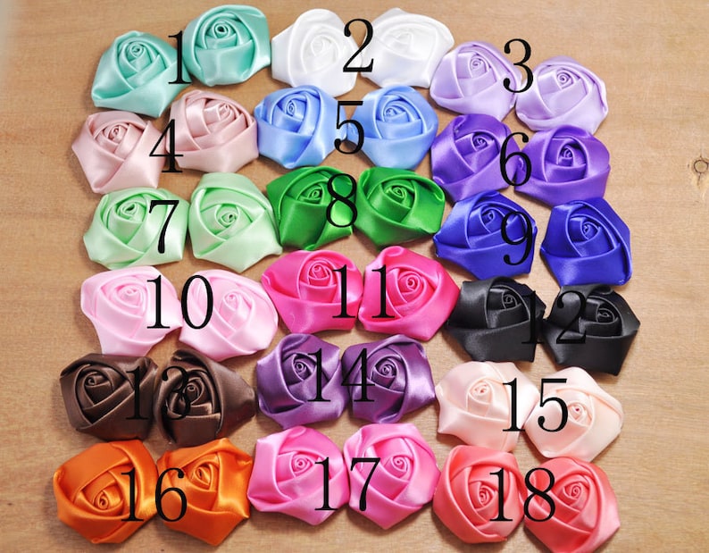 May include: Eighteen satin fabric rosettes in various colors, numbered 1 through 18. The rosettes are arranged in three rows of six rosettes each.