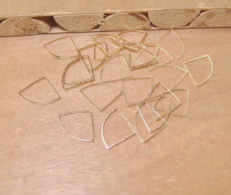 May include: A pile of gold-colored metal half-circle shapes, likely for jewelry making.