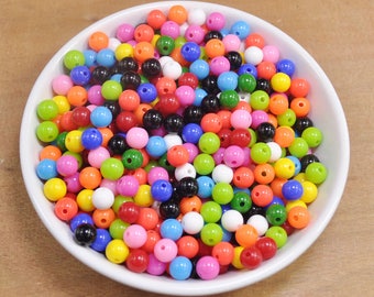 May include: A bowl filled with colorful plastic beads in various shades of red, orange, yellow, green, blue, purple, black, and white.