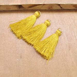 May include: Three gold tassel trim embellishments with gold metal rings.