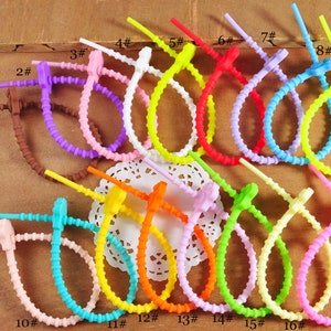 Puede incluir: Surtido de 17 bridas de cable de silicona de colores, numeradas del 1 al 17. Las bridas son de varios colores, incluyendo rosa, azul, amarillo, verde, naranja y morado.