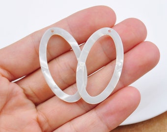 May include: Two white oval-shaped acrylic blanks with a hole in the top. The blanks are smooth and have a marbled effect.
