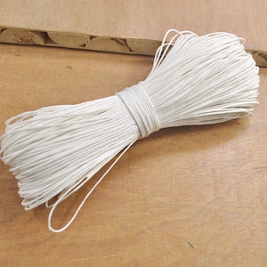 Pode incluir: Uma bobina de barbante branco, um tipo de corda usada para artesanato e embalagem.