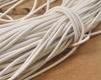 May include: A close-up of a large bundle of white elastic cord. The cord is tightly wound and appears to be made of a soft, flexible material.