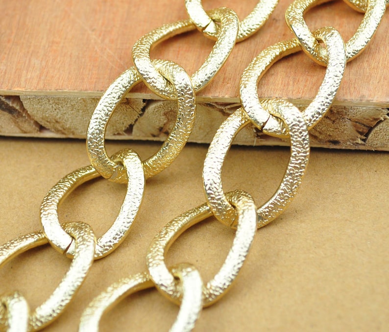 May include: Gold chain with textured oval links. The chain is thick and has a shiny finish.