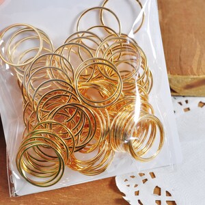 May include: A close-up of a bag filled with gold jump rings. The rings are various sizes and are perfect for jewelry making.