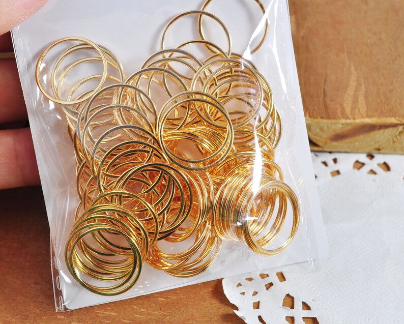 May include: A close-up of a bag filled with gold jump rings. The rings are various sizes and are perfect for jewelry making.