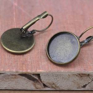 Puede incluir: Dos ajustes de pendientes de color bronce con una base redonda y plana y un bucle de alambre para sujetar un colgante. Los ajustes están diseñados para usarse con cabujones de vidrio.