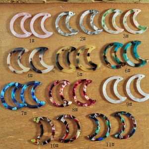 May include: Twelve pairs of crescent moon-shaped acrylic hair clips in various colors and patterns. The clips are numbered 1 through 11.