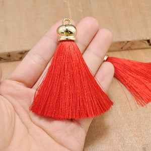 May include: Red tassel with a gold metal top. The tassel is made of soft, silky threads and is approximately 2 inches long.