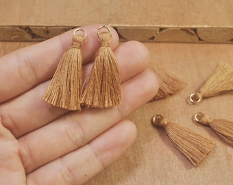 May include: Five brown tassel trim with gold rings. The tassels are approximately 1 inch long.