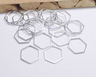 Peut inclure: Un tas de anneaux de saut hexagonaux en métal argenté. Les anneaux sont de différentes tailles et sont dispersés sur une surface blanche.